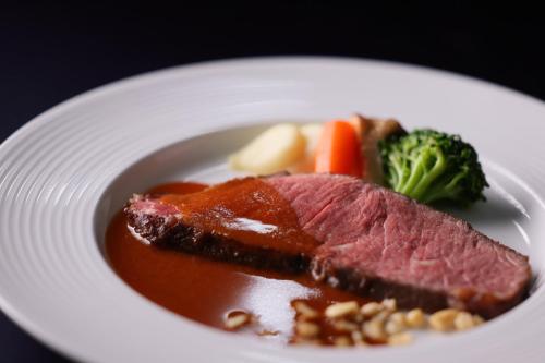 a white plate with meat and vegetables and sauce at ANA Crowne Plaza Narita by IHG in Narita