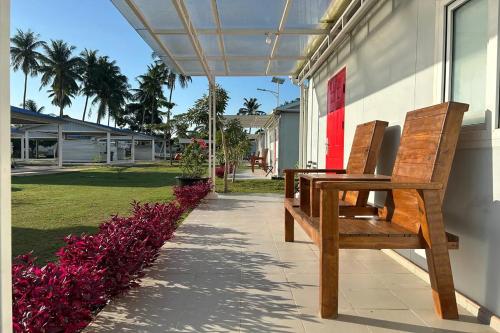 a wooden bench sitting outside of a building with purple flowers at Saga Village Hotel & Resort Bintan in Pulau Sekerah