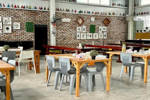 a restaurant with wooden tables and chairs and a brick wall at Saga Village Hotel & Resort Bintan in Pulau Sekerah