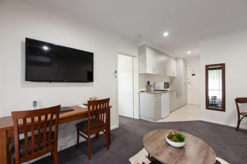 a living room with a table and a kitchen at Addison Motor Inn in Shepparton