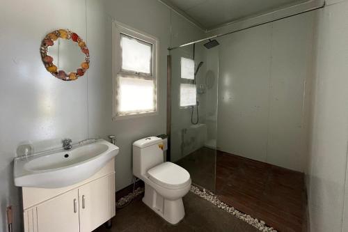 a bathroom with a toilet and a sink and a mirror at Saga Village Hotel & Resort Bintan in Pulau Sekerah