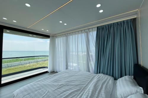 a bedroom with a bed and a large window at Saga Village Hotel & Resort Bintan in Pulau Sekerah