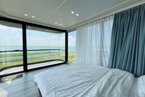 a bedroom with a bed and a large window at Saga Village Hotel & Resort Bintan in Pulau Sekerah