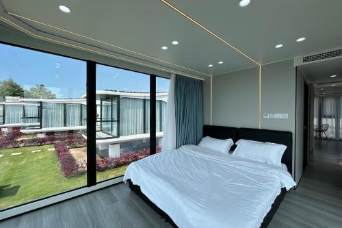 a bedroom with a bed and a large window at Saga Village Hotel & Resort Bintan in Pulau Sekerah