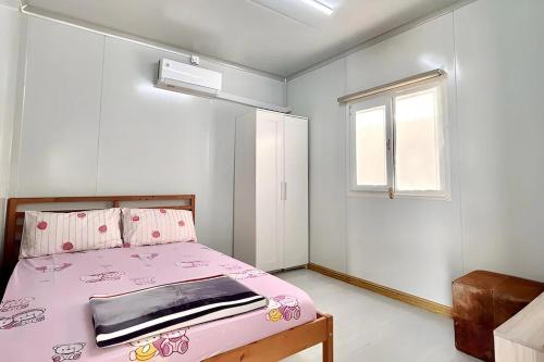 a bedroom with a pink bed and a window at Saga Village Hotel & Resort Bintan in Pulau Sekerah