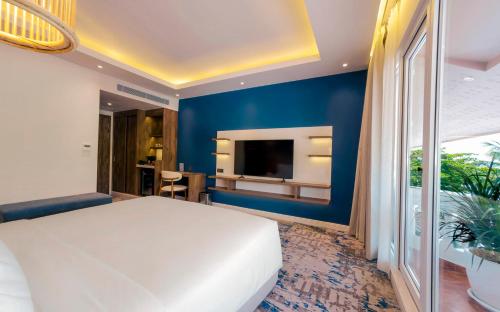 a bedroom with a white bed and a blue wall at Queenco Hotel & Casino in Sihanoukville