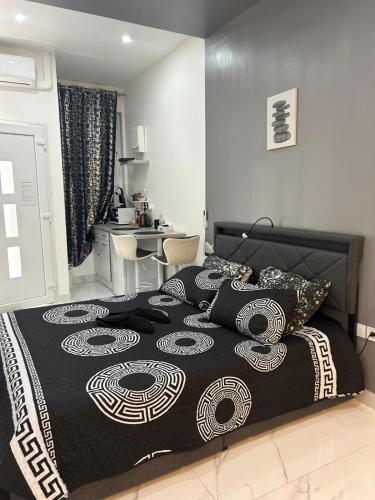 a bedroom with a bed with a black and white bedspread at Suite Zen Amaryllis Jacuzzi TV Integrée Clim Wifi Béziers Centre Arrivée Autonome 24h24 in Béziers