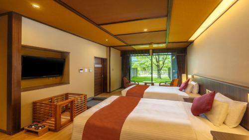 a hotel room with two beds and a flat screen tv at KAMENOI HOTEL Ome in Ome