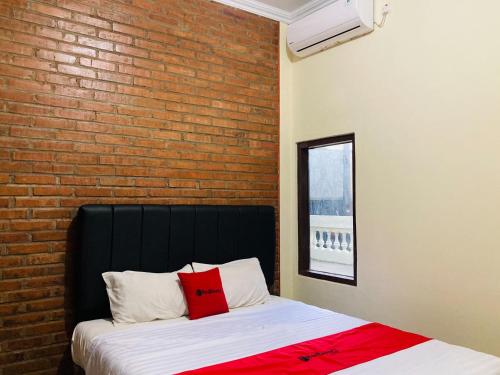 a bed in a room with a brick wall at RedDoorz near Jalan Malioboro Area in Ngabean