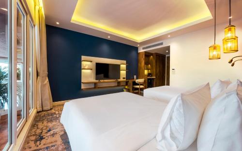 a bedroom with two white beds and a blue wall at Queenco Hotel & Casino in Sihanoukville