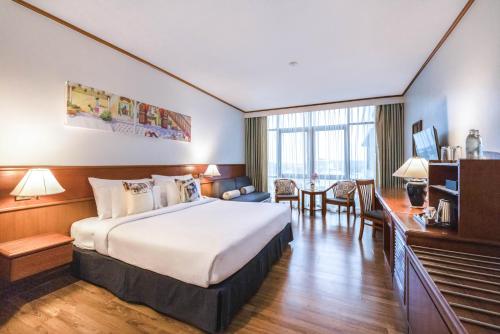 a hotel room with a large bed and a desk at Royal Phuket City Hotel in Phuket Town