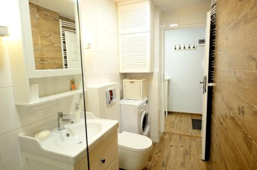 a white bathroom with a sink and a toilet at Victus Apartamenty, Apartament Askja in Sopot