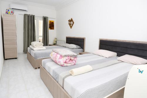 three beds in a room with white walls at Residence Lyne in Kairouan