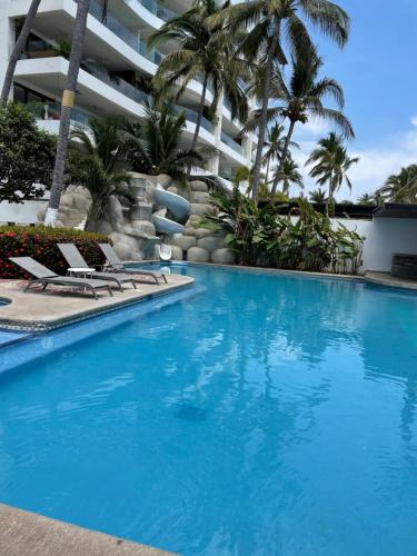Una piscina con sillas y un edificio. en Penthouse on the shore of the pacific in Bucerias, en Bucerías