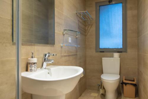 a bathroom with a sink and a toilet with a window at CasaNova Airport Suites in Accra