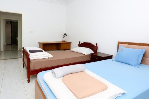 a room with two beds and a desk and a table at Residence Lyne in Kairouan