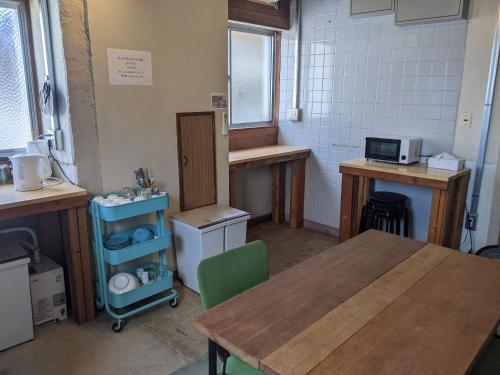 a kitchen with a wooden table and a table and a room at Tomarotto Hostel in Takayama