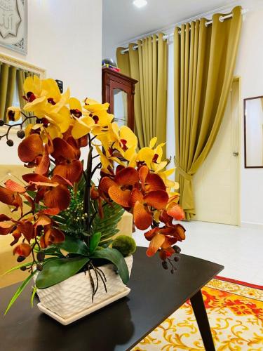a vase filled with yellow and orange flowers on a table at EM Rumah Inap SueKori Jeli in Jeli