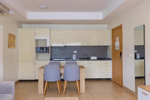 a kitchen with a wooden table and two blue chairs at CasaNova Airport Suites in Accra
