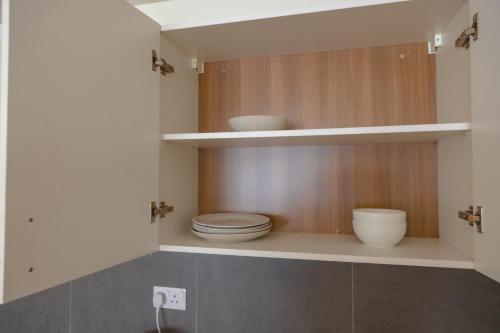a bathroom with a toilet and bowls on shelves at CasaNova Airport Suites in Accra