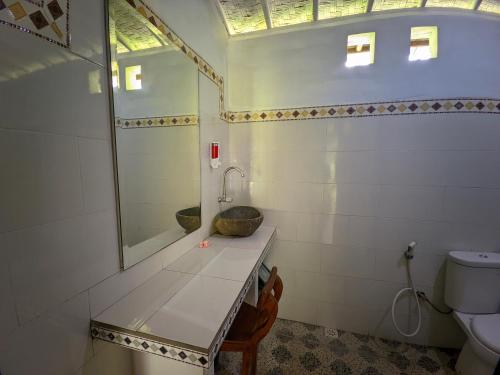 a bathroom with a sink and a mirror and a toilet at Dangin Kubu in Toyapakeh