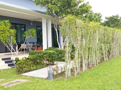 a garden with white trees in front of a house at Moonlight Cottage in Ban Pa Khlok
