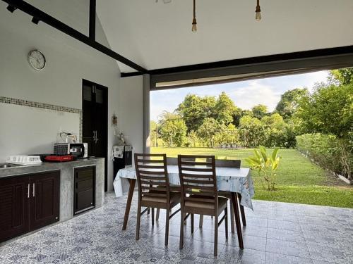 a kitchen with a table and chairs and a large window at Moonlight Cottage in Ban Pa Khlok
