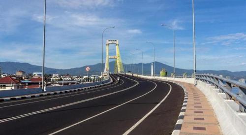 a bridge with a person walking across a highway at Hotel Minahasa in Manado