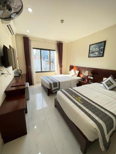 a hotel room with two beds and a television at New Sun Hotel in Ha Long