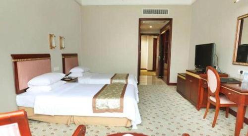 a hotel room with a bed and a desk and a television at Quanzhou Royal Prince Hotel in Quanzhou