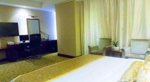 a hotel room with a large bed and a living room at Jincheng Pacific Hotel in Jincheng