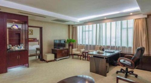a hotel room with a desk and a living room at Jincheng Pacific Hotel in Jincheng