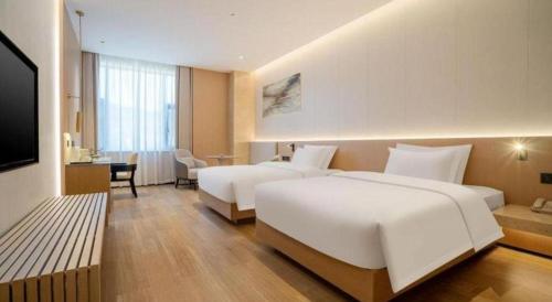 a hotel room with two beds and a television at Lijiang Waika Hotel in Lijiang