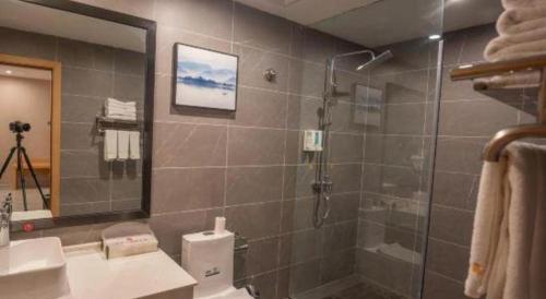 a bathroom with a shower and a toilet and a sink at Lijiang Waika Hotel in Lijiang