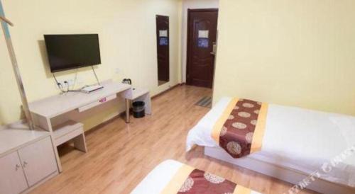 a bedroom with a bed and a desk with a television at Kunlun Leju Business Hotel Kaifeng Gulou in Kaifeng