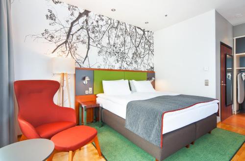 a bedroom with a bed and a red chair at Holiday Inn Helsinki City Centre, an IHG Hotel in Helsinki