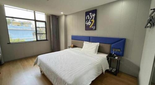 a bedroom with a large bed with a blue headboard at 7 Days Inn Xingyi Wanfenglin Xiawutun in Xiawutun