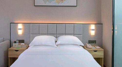a bedroom with a large white bed with two night stands at danfeng kelly hotel in Shenzhen