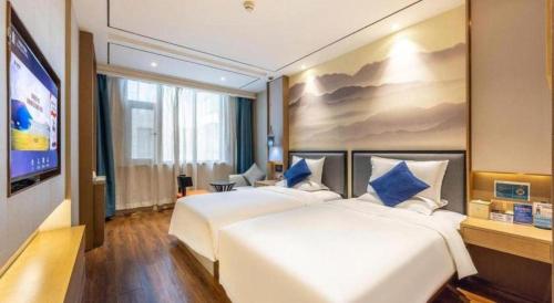 a hotel room with two beds and a flat screen tv at East Queen Hotel (Xi'an Beimen Metro Station) in Xi'an