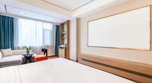 a bedroom with a large white bed and a couch at East Queen Hotel (Xi'an Beimen Metro Station) in Xi'an