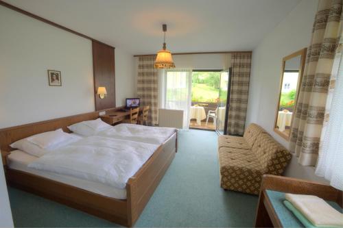 a bedroom with a large white bed and a chair at Urlaubshotel Binder in Büchlberg