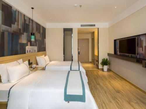 a hotel room with two beds and a flat screen tv at Echarm Hotel Changsha High-speed Railway Station in Changsha