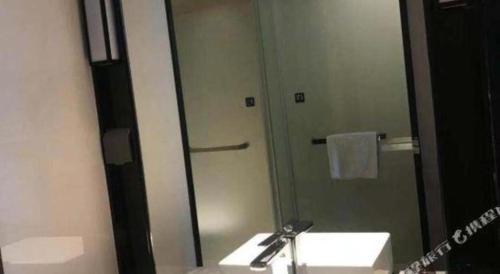 a bathroom with a sink and a shower with a mirror at Echarm Hotel Changde Taoyuan Walking Street Jinyuan Tower in Changde