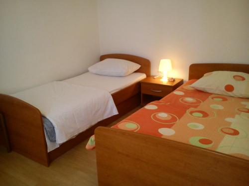 two beds in a small room with a lamp on a table at Apartments Marko in Vrsi