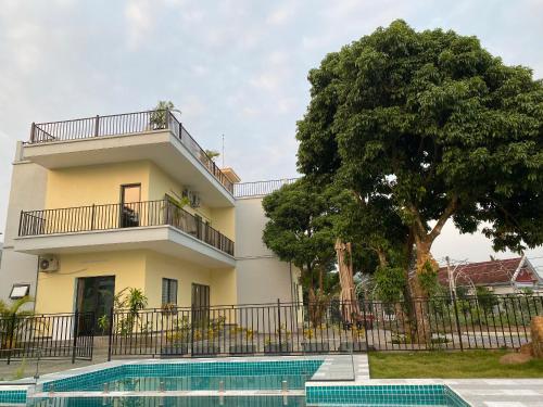 a house with a tree and a swimming pool at Kame Healing Garden in Ba Vì