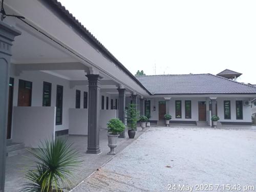 a white house with potted plants in a courtyard at Suria guesthouse in Kampung Raja