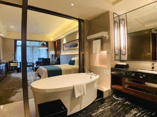 une salle de bain avec une baignoire, un lit et un lavabo dans l'établissement Country Garden Phoenix Hotel Yiyang, à Heshanqu