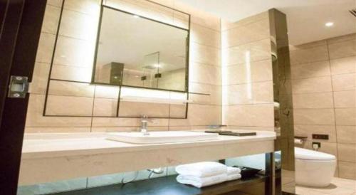 a bathroom with a sink and a mirror and a toilet at Xana Lite Hotelle Yan'an Baota Mountain in Yan'an