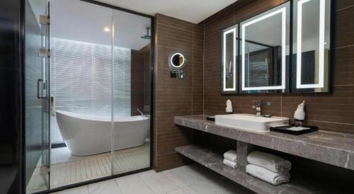 a bathroom with a tub and a sink and a shower at Xana Hotelle Shenzheng South Station Foxconn in Shenzhen