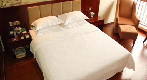 a bedroom with a large white bed and a chair at GreenTree Inn Anqing Yingbin Dong Road High-Speed Railway Station in Anqing